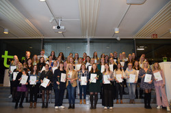 Gruppenfoto der Absolventinnen, Absolventen, Promovendinnen und Promovenden. Alle halten ihre Abschlussurkunden in der Hand.