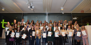 Gruppenfoto der Absolventinnen, Absolventen, Promovendinnen und Promovenden. Alle halten ihre Abschlussurkunden in der Hand.