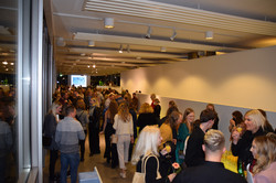 Gruppen von Personen stehen nach der Abschlussfeier zusammen und unterhalten sich, einige bedienen sich am Buffet.