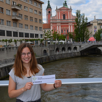 Studentin mit Fakultätslogo auf einer Brücke in Ljubljana