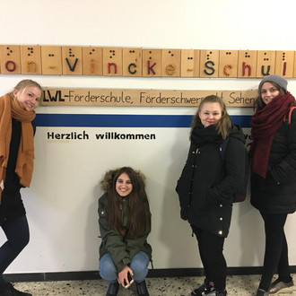Studentinnen stehen in der Van-Vincke-Schule vor dem Schriftzug der Schule