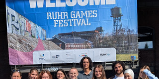 10 Personen vor einem Plakat der FISU World University Games