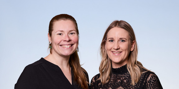 Zwei Frauen schauen erfreut Richtung Kamera.