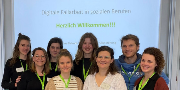 Acht junge Frauen stehen vor einer Präsentation mit der Aufschrift "Herzlich Willkommen!" und den Logos der TU Dortmund und des Projekts RehaLand.