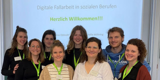Acht junge Frauen stehen vor einer Präsentation mit der Aufschrift "Herzlich Willkommen!" und den Logos der TU Dortmund und des Projekts RehaLand.