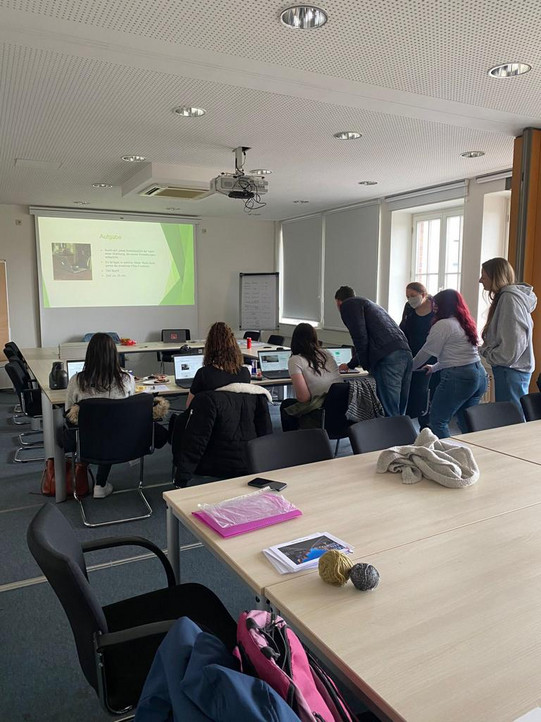 Das Team Wohnungssuche mit der JVA Iserlohn bespricht sich. Im Hintergrund wird eine Präsentation an die Wand übertragen.