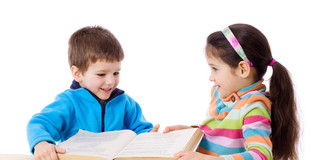 Zwei Kinder, die gemeinsam ein großes aufgeschlagenes Buch halten