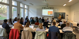 Mehrere Personen sitzen in einem Raum und schauen sich eine Präsentation an.