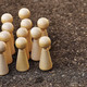 Eine Gruppe von Holzfiguren steht einer einzelnen Holzfigur gegenüber