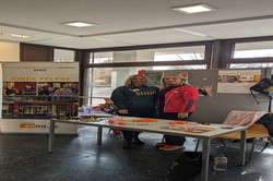 Zwei Personen stehen hinter einem Tisch des Wohn- und Begegnungszentrums Zehnthof (WBZ) in Dortmund. Der Stand trägt das Motto „Junge Pflege“; auf dem Tisch liegen orangefarbene Werbeartikel wie Bälle und Schlüsselanhänger.