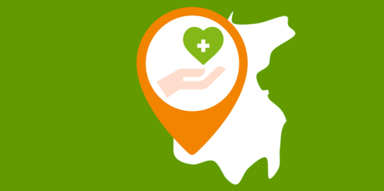 Ausschnitt einer Landkarte, auf dem eine Hand zu sehen ist, die ein grünes Herz mit einem weißen Kreuz hält