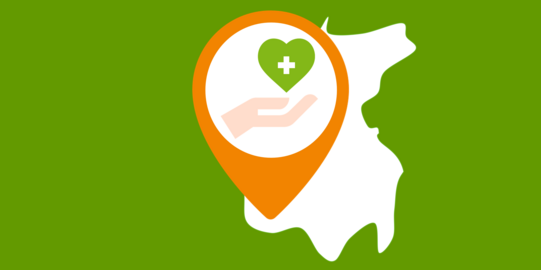 Ausschnitt einer Landkarte, auf dem eine Hand zu sehen ist, die ein grünes Herz mit einem weißen Kreuz hält