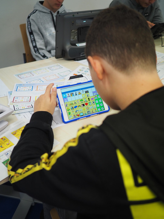 Es ist ein Junge von hinten zu sehen, der ein Tablet bedient.