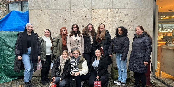 Abgebildet sind elf Personen des Online Week Teams vor einer Hauswand.