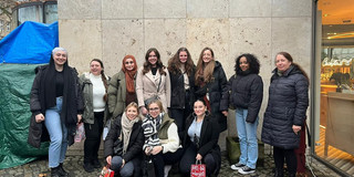 Abgebildet sind elf Personen des Online Week Teams vor einer Hauswand.