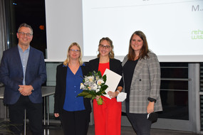 Zu sehen sind vier Personen (von links nach rechts: Prof. Dr. Tobias Kuhn, Prof. Dr. Olga Kunina-Habenicht, Lotte-Kaliski-Preisträgerin Larissa Pliska und Teresa Sator). Die Preisträgerin hält einen Blumenstrauß und eine Urkunde in der Hand.