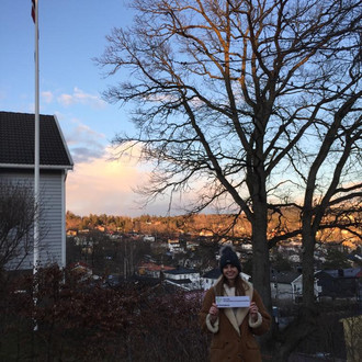 Studentin mit Fakultätslogo vor Norwegischer Flagge mit Aussicht auf Ort