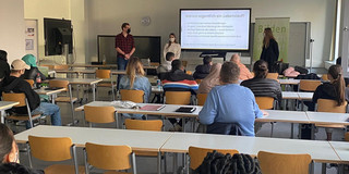Drei Teilnehmerinnen und Teilnehmer der Get Online Week stehen vor eine Schulklasse, auf dem Smartboard im Hintergrund ist die Überschrift "Warum eigentlich ein Lebenslauf?" zu erkennen