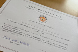 Das Bild zeigt ein Teilnahmezertifikat, das für einen Kurs über Schönheitsideale auf Social Media ausgestellt wurde. Das Zertifikat ist auf hochwertigem Papier gedruckt und enthält den Titel „TEILNAHMEZERTIFIKAT“ in großen Buchstaben. In der Mitte befindet sich ein Symbol, das auf die Veranstaltung hinweist, sowie eine Bestätigung, dass die Teilnehmerin oder der Teilnehmer mit großem Engagement Kenntnisse und Wissen über Körperbilder und deren Einfluss auf die Selbstwahrnehmung erworben hat.
