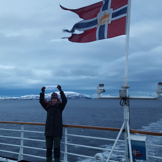 Studentin mit Fakultätslogo auf einem Schiff in Norwegen