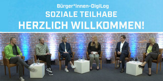 Gruppenbild der Referentinnen und Referenten während einer Diskussion. Jeder sitzt auf einem eigenen Stuhl, zwischen einigen Stühlen stehen kleine Tische mit Getränken.