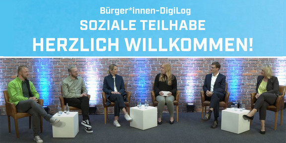 Gruppenbild der Referentinnen und Referenten während einer Diskussion. Jeder sitzt auf einem eigenen Stuhl, zwischen einigen Stühlen stehen kleine Tische mit Getränken.