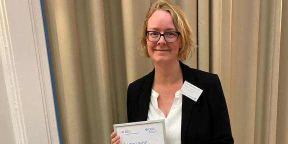 Das Foto zeigt Prof. Dr. Sarah Weigelt, die in ihren Händen die Preisurkunde hält.