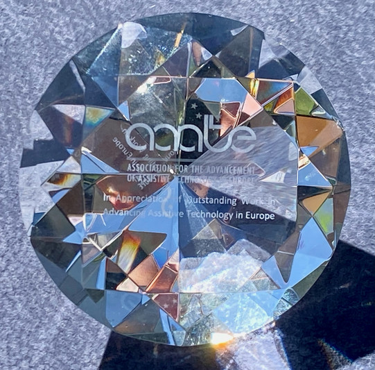Auf dem Foto ist der Award erkennbar. Er ähnelt einem durchsichtigen Diamanten und ist beschriftet. Gut erkennbar in großer Schrift findet man den Namen des Awards: aaate.