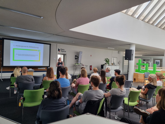 Innovationsakademie Vortrag Ungefähr 40 Personen sitzen in Stuhlreihen mit Blick in Richtung Vortrag. Es wird eine Präsentation an die Wand projiziert.