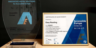 Trophäe und Siegerurkunde für das Forschungsprojekt "Easy Reading" stehen nebeneinander auf einem Tisch