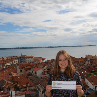 Studentin mit Fakultätslogo über den Dächern von Ljubljana