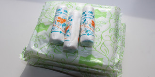 Drei Tampons liegen auf einem Stapel verpackter Binden