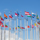 Flag poles with various european flags in front of a blue sky, arranged in a circular pattern
