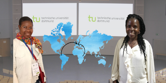 Zu sehen sind zwei Wissenschaftlerinnen welche lächelnd links und rechts vor Ihrem an eine weiße Tafel projezierten Vortrag stehen.