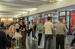 Das Bild zeigt eine Gruppe von Menschen, die sich im Foyer des EF50 versammelt haben. Die Personen stehen in lockeren Gruppen zusammen und unterhalten sich.
