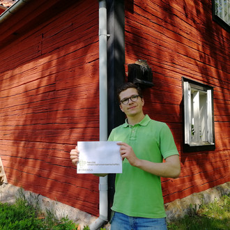 Student mit Fakultätslogo vor einem Haus in Linköping