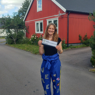 Studentin mit Fakultätslogo vor einem Haus in Linköping