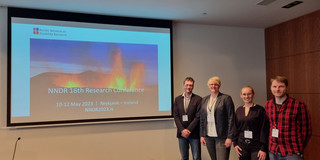 Vier Personen stehen vor einer Power Point Präsentation auf der 16. Research Conference des Nordic Network on Disability Research (NNDR). Zu sehen sind von links nach recht Bastian Pelka, Lena Hünefeld, Sophie Teborg und Frederik Winkelkotte.