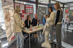 Mehrere Menschen unterhalten sich an einem Infostand des AWO-Inklusionsprojekts „NeuEinstieg“.