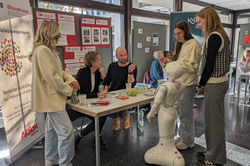 Mehrere Menschen unterhalten sich an einem Infostand des AWO-Inklusionsprojekts „NeuEinstieg“.