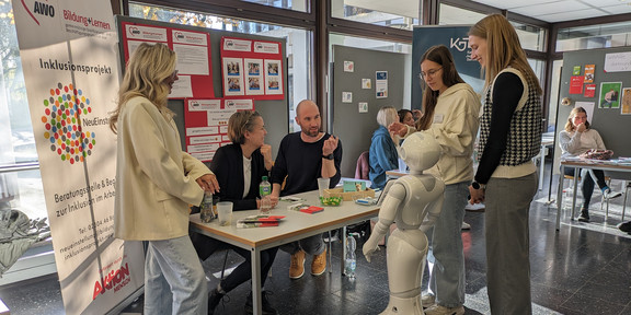 Mehrere Menschen unterhalten sich an einem Infostand des AWO-Inklusionsprojekts „NeuEinstieg“.