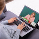 Frau sitzt am Laptop und hält eine Videokonferenz mit einer anderen Frau ab