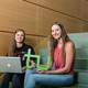 Zwei Studentinnen sitzen mit Laptop und TU-Logo auf einer Treppe.