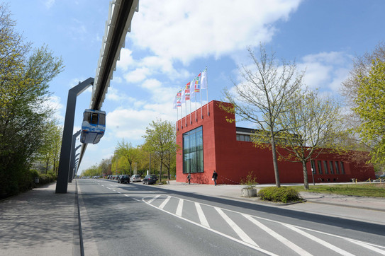 Red building within trees and the H-Bahn