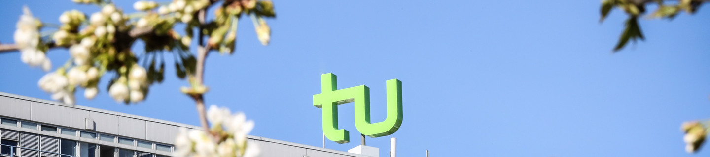 Kirschblüten und das Mathegebäude mit dem TU-Logo im Hintergrund.